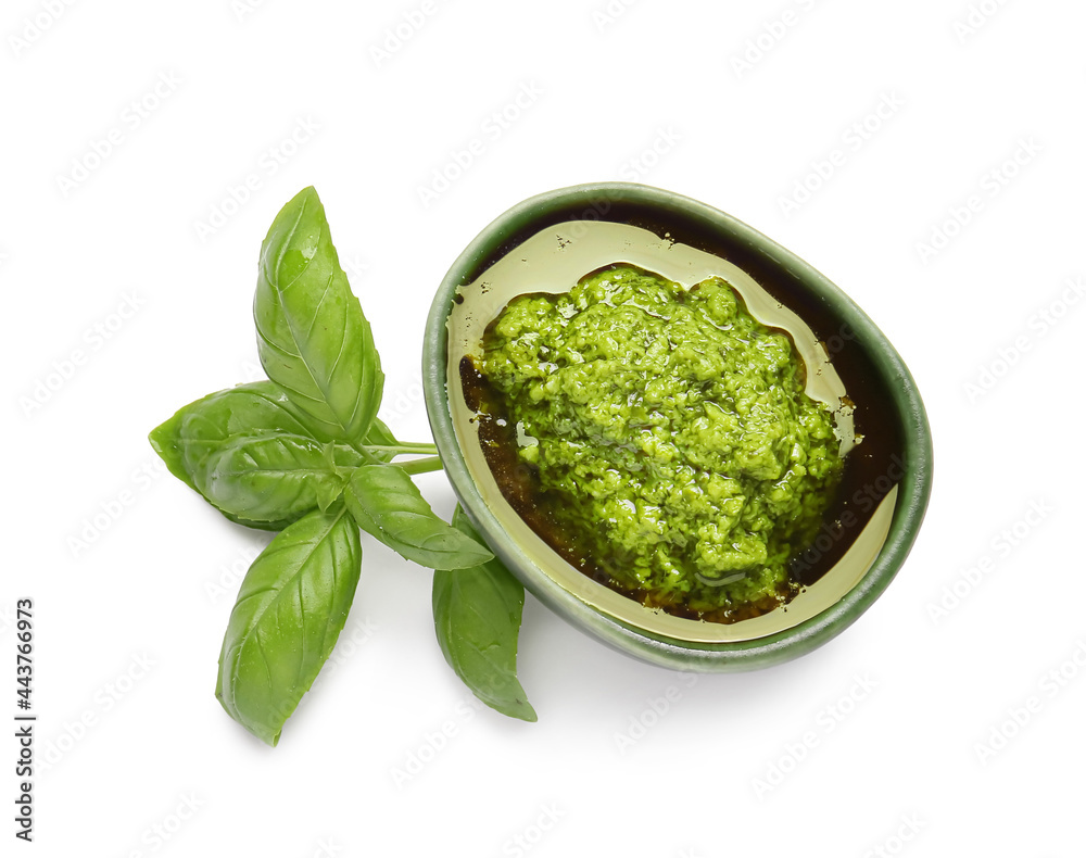 Bowl with fresh pesto sauce and basil leaves on white background