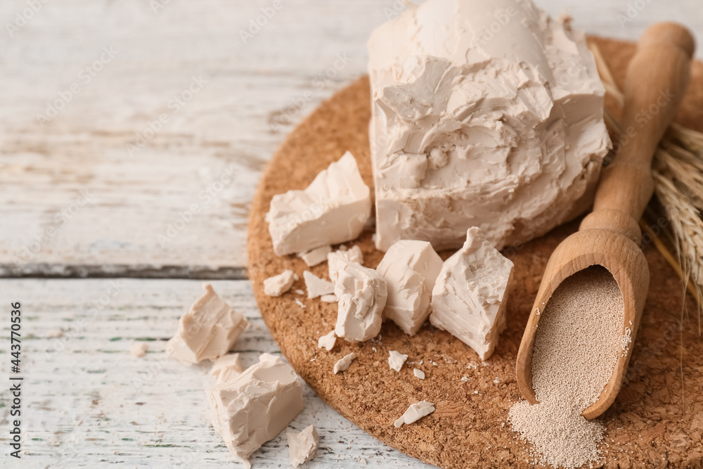 Board with fresh and dry yeast on light wooden background