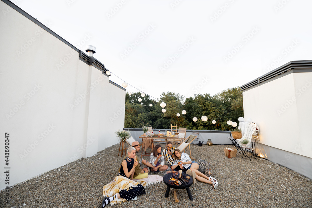 Beautiful rooftop terrace of a country house with friends having a picnic, sitting together by the f