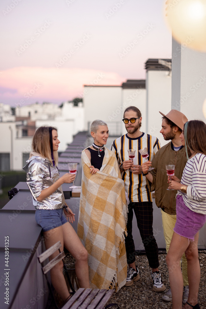 Young stylish friends hang out together, talk and having fun on a rooftop terrace with beautiful vie