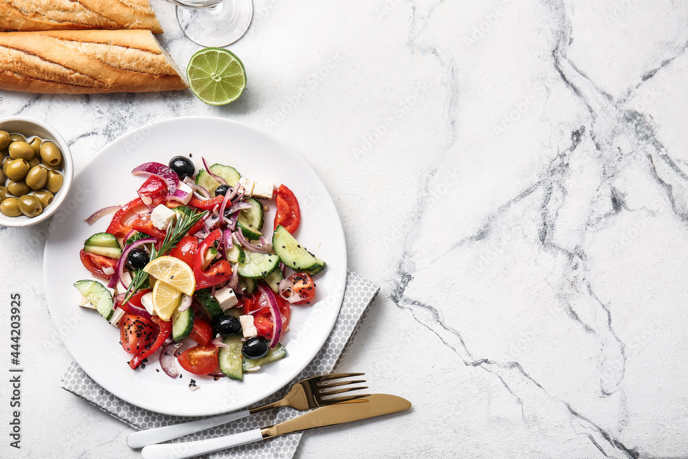 Plate with tasty Greek salad, olives and bread on light background