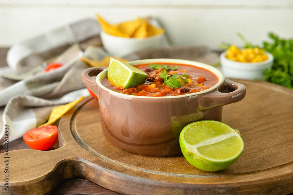 Pot with delicious chili con carne on wooden background