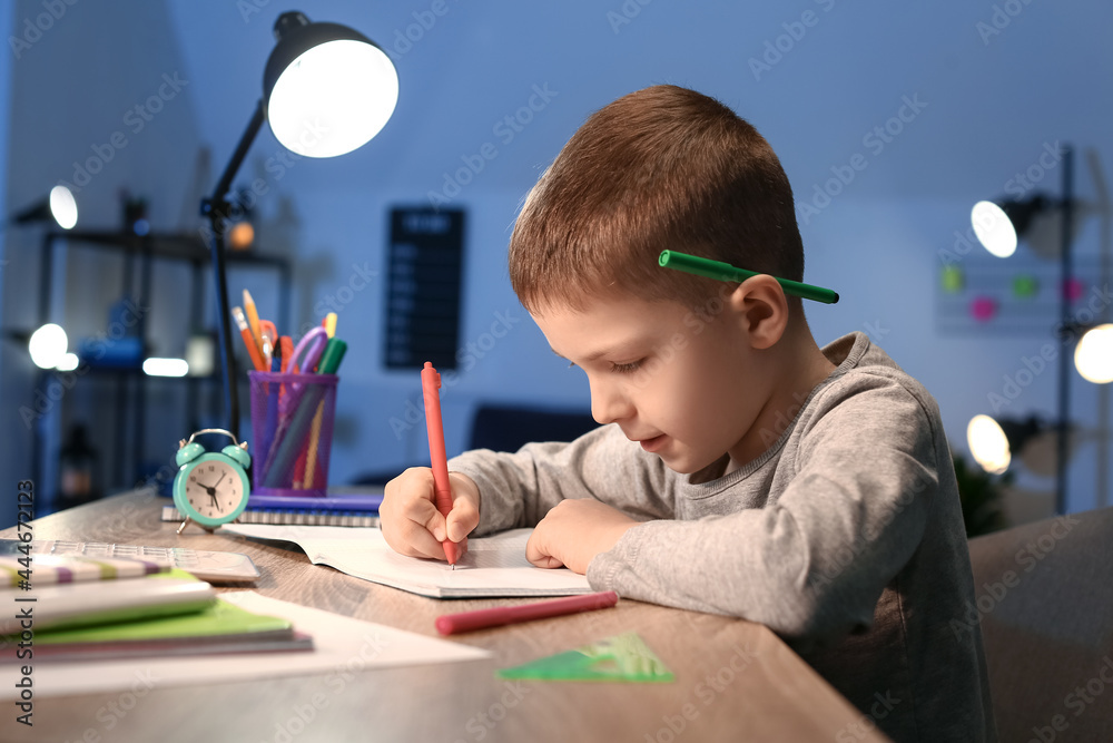 Little boy doing homework at home late in evening