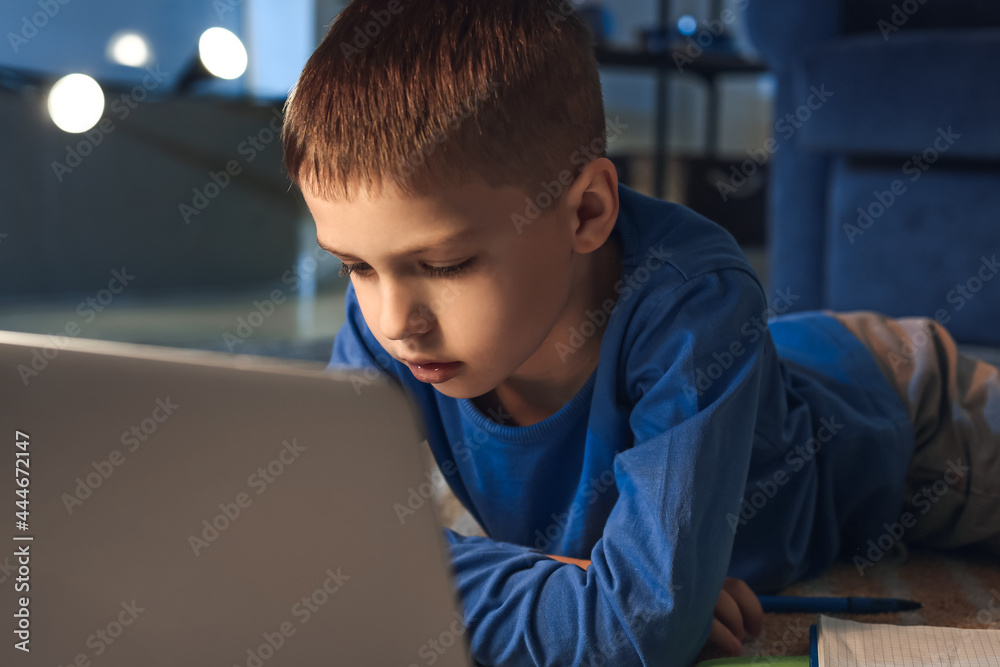 Little boy doing homework at home late in evening