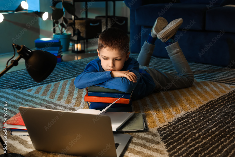 Little boy doing homework at home late in evening