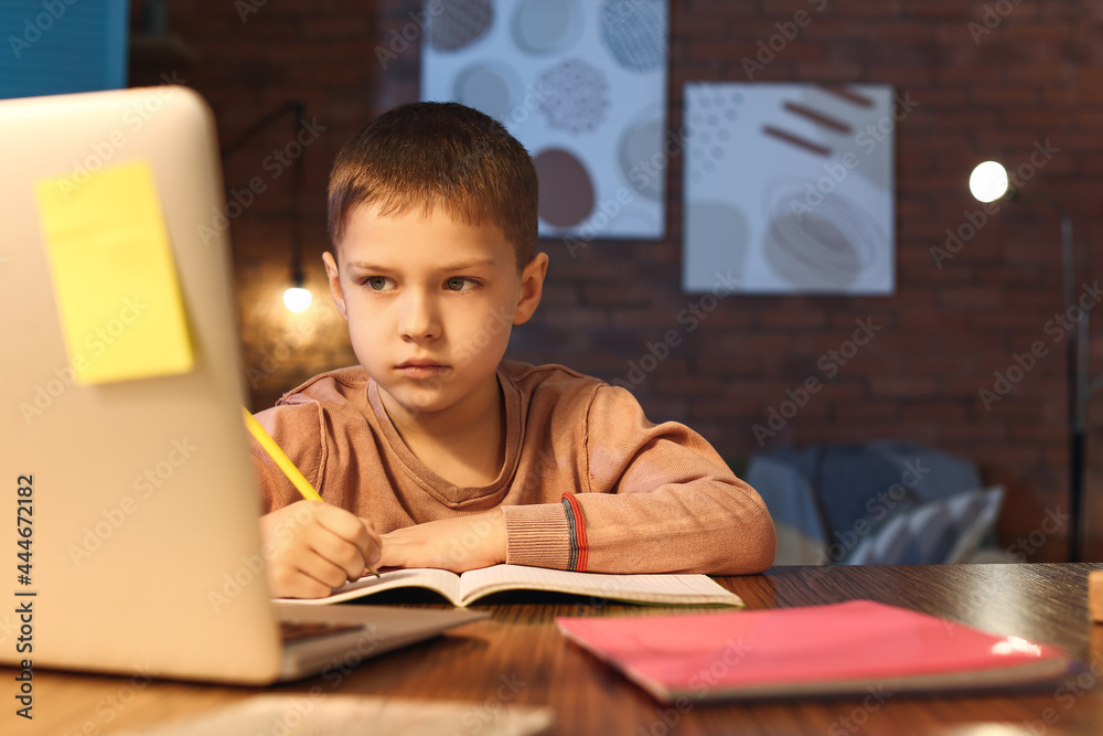 Little boy doing homework at home late in evening