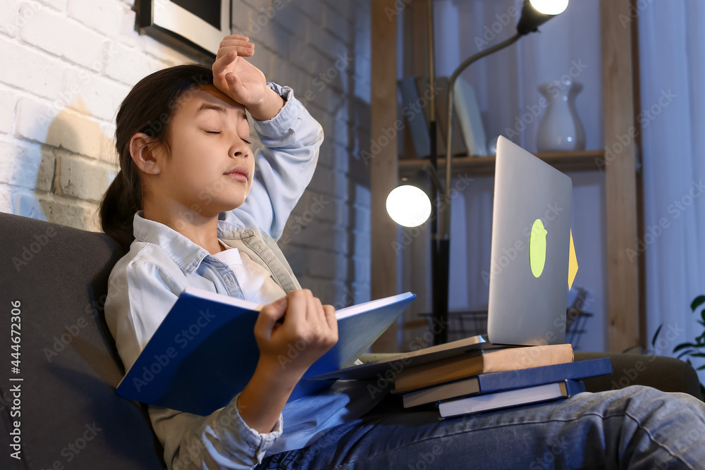 Little girl tired of doing homework at home late in evening