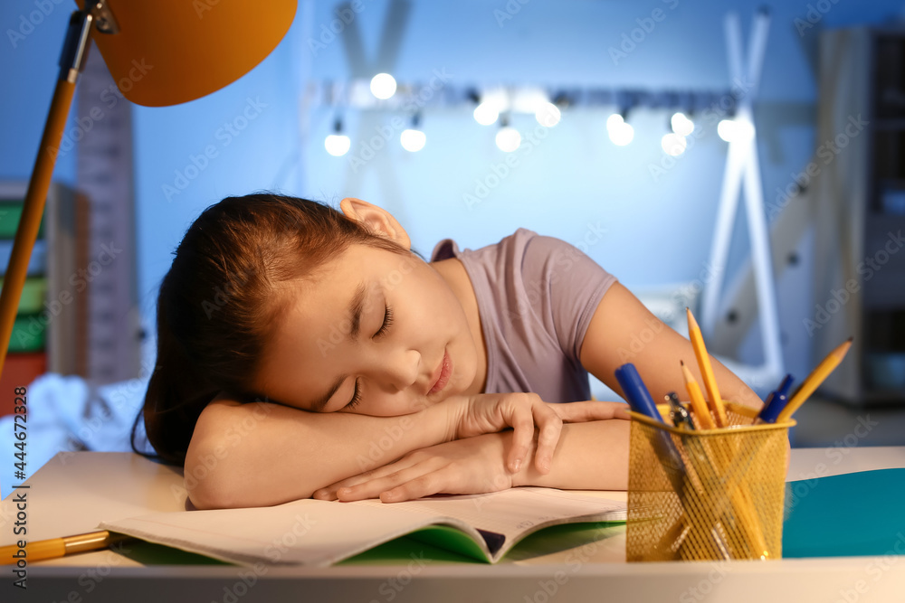 Little girl tired of doing homework at home late in evening