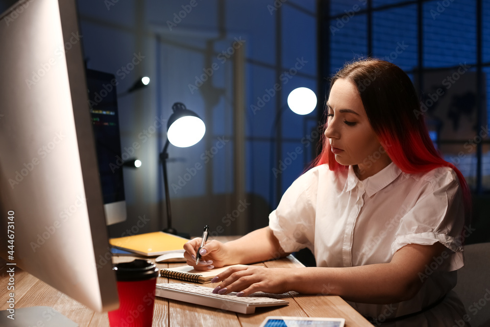 Female programmer working with computer in office at night