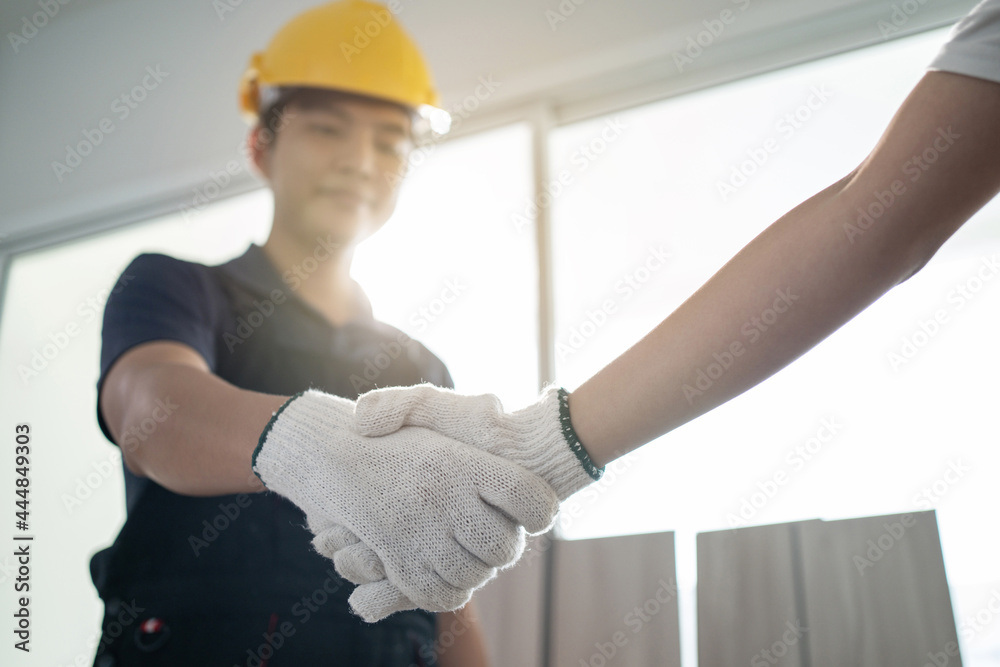 Asian Construction worker greeting by handshake with builder at home.