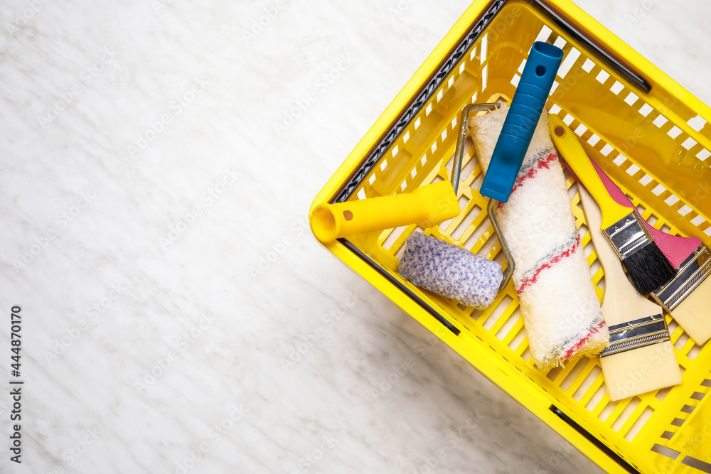 Shopping basket with painters supplies on light background