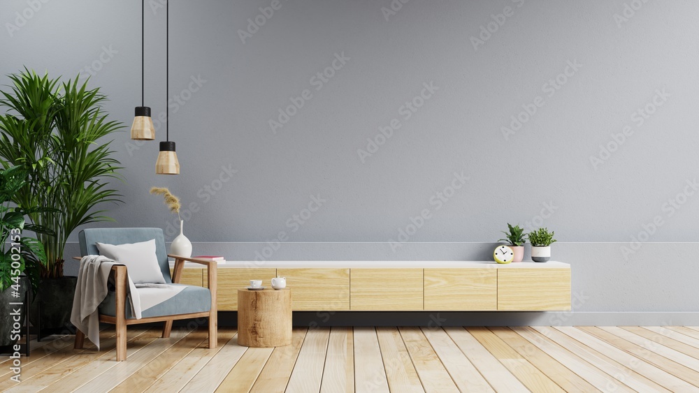 Mockup cabinet in modern living room with blue armchair and plant on dark gray wall background.