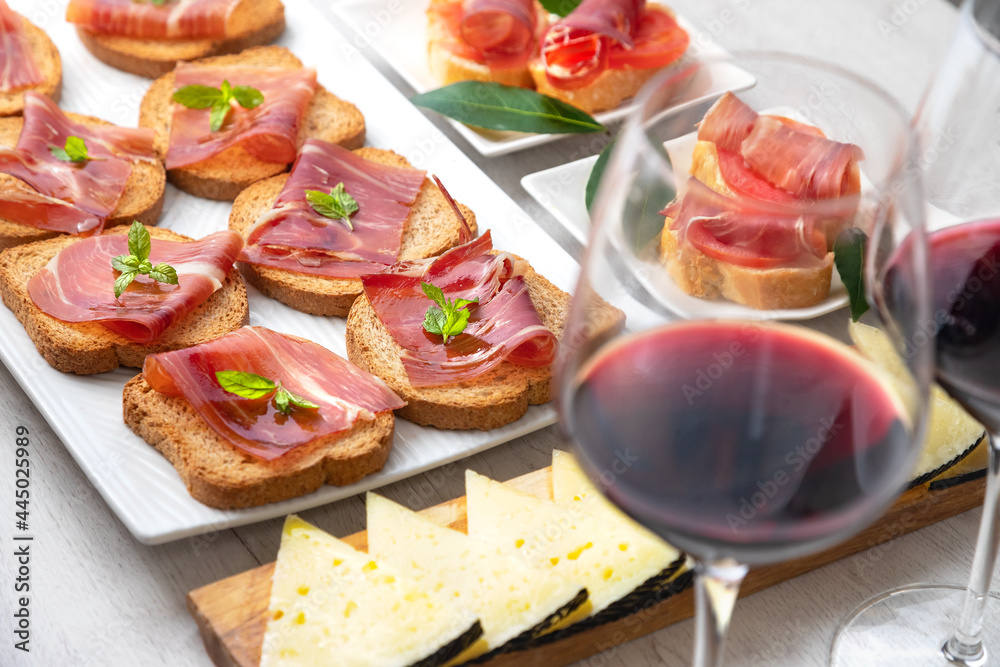 Spanish tapas and appetizers.Tapas and appetizers of Iberian ham with a glass of wine, ripe tomatoes