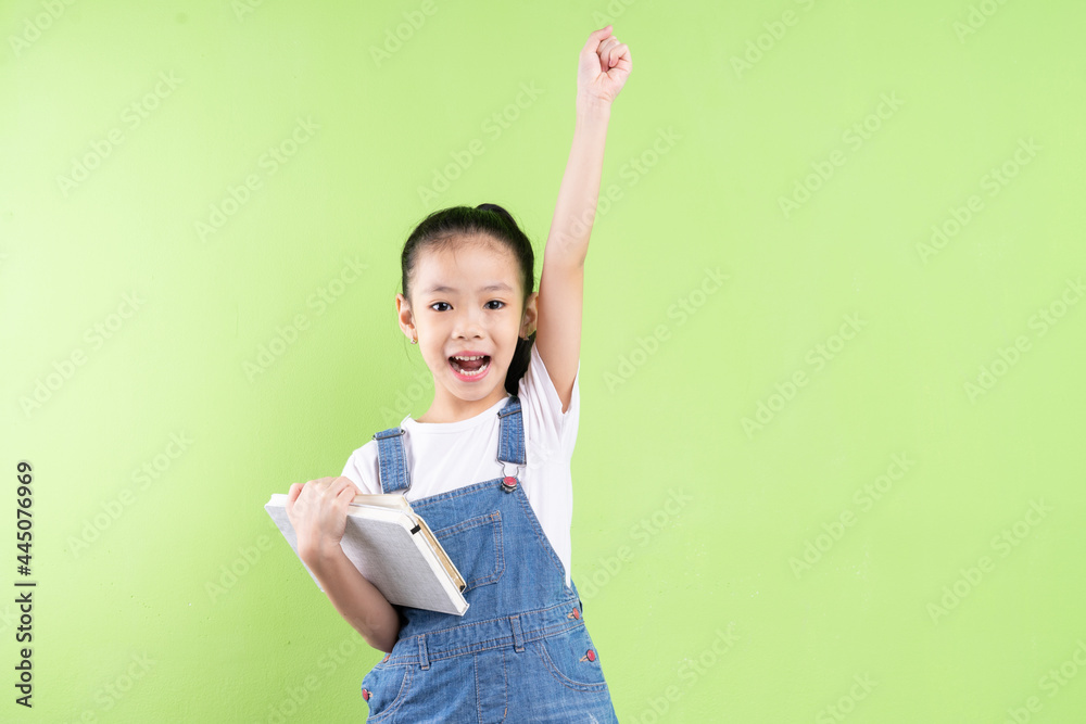 Portrait of Asian child holding book on green background