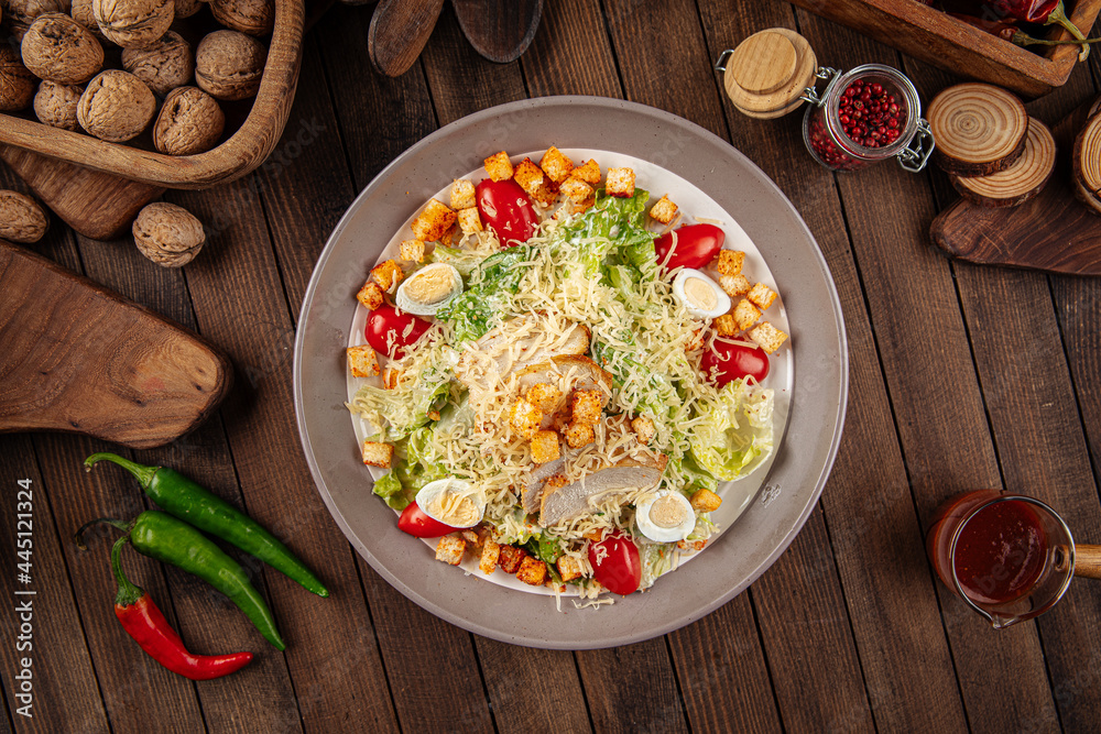 Caesar salad with shrimp and croutons on wooden background