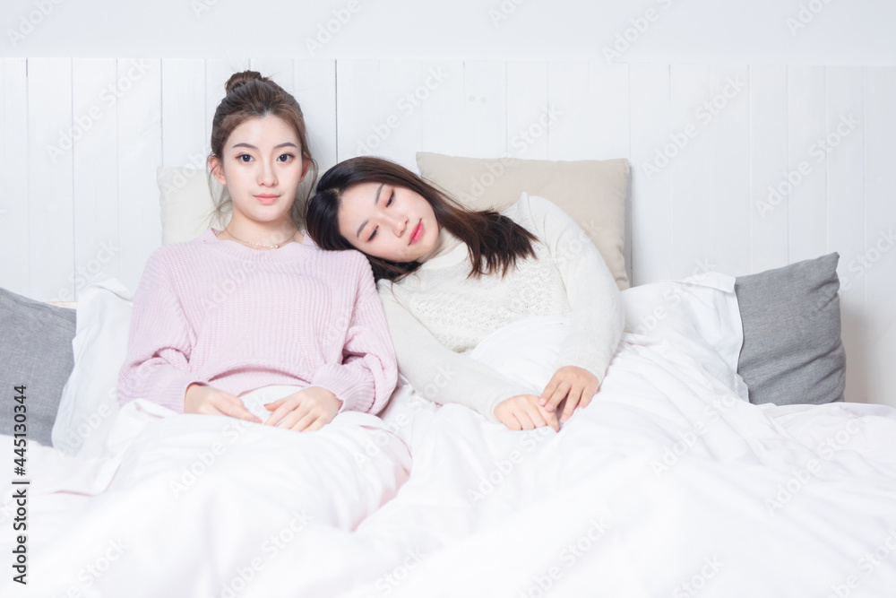 Two beauties sitting on the bedside talking