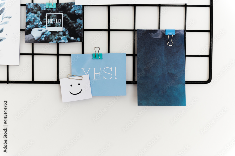 Postcard and Pictures on a Rack Against a White Wall