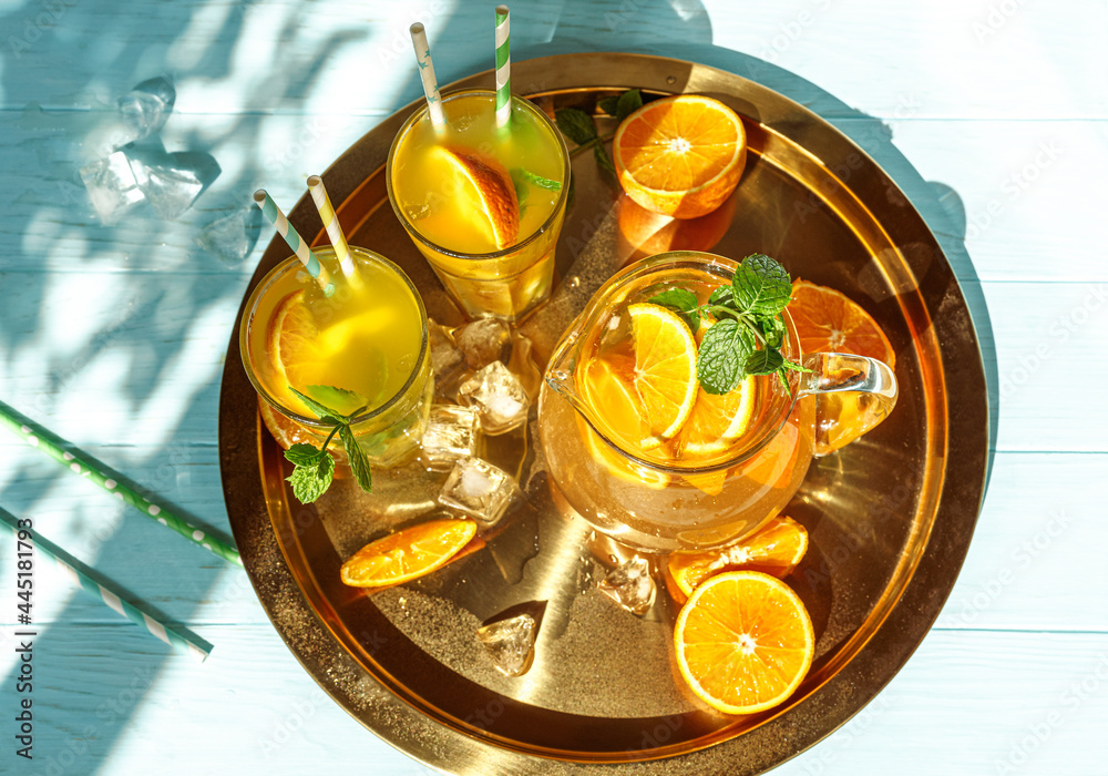 Glasses of lemonade with oranges, ice cubes and mint leaves on golden plate. Top view of lemonade on