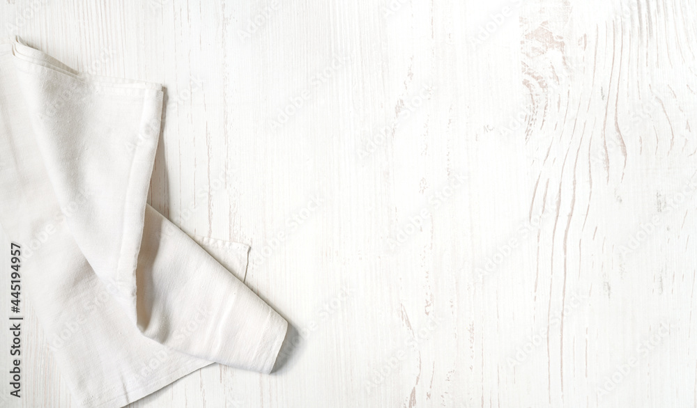 White linen napkin on wooden background with copy space. Top view flat lay. Kitchen napkin on white 