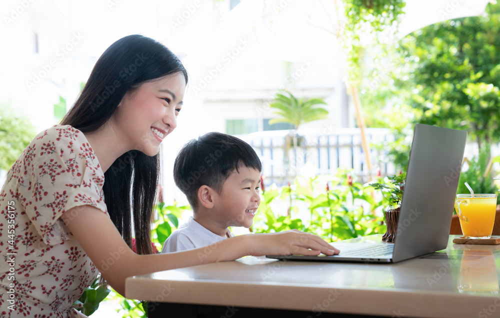 年轻的亚洲母子在家一起使用笔记本电脑学习