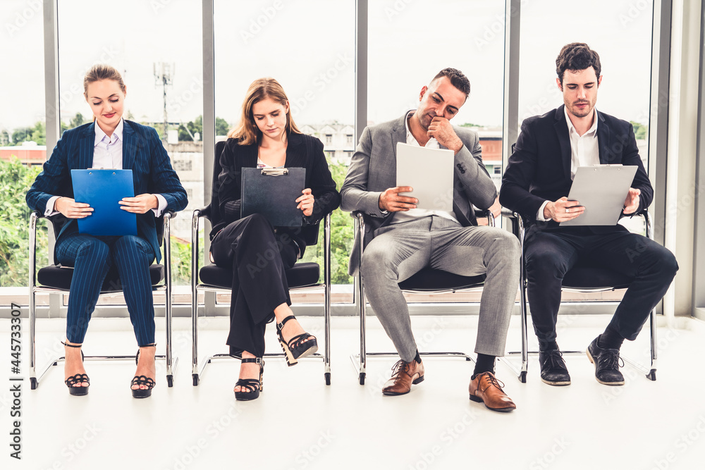 Businesswomen and businessmen holding resume CV folder while waiting on chairs in office for job int