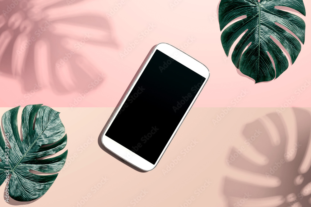 Smartphone with tropical monstera leaves and shadow