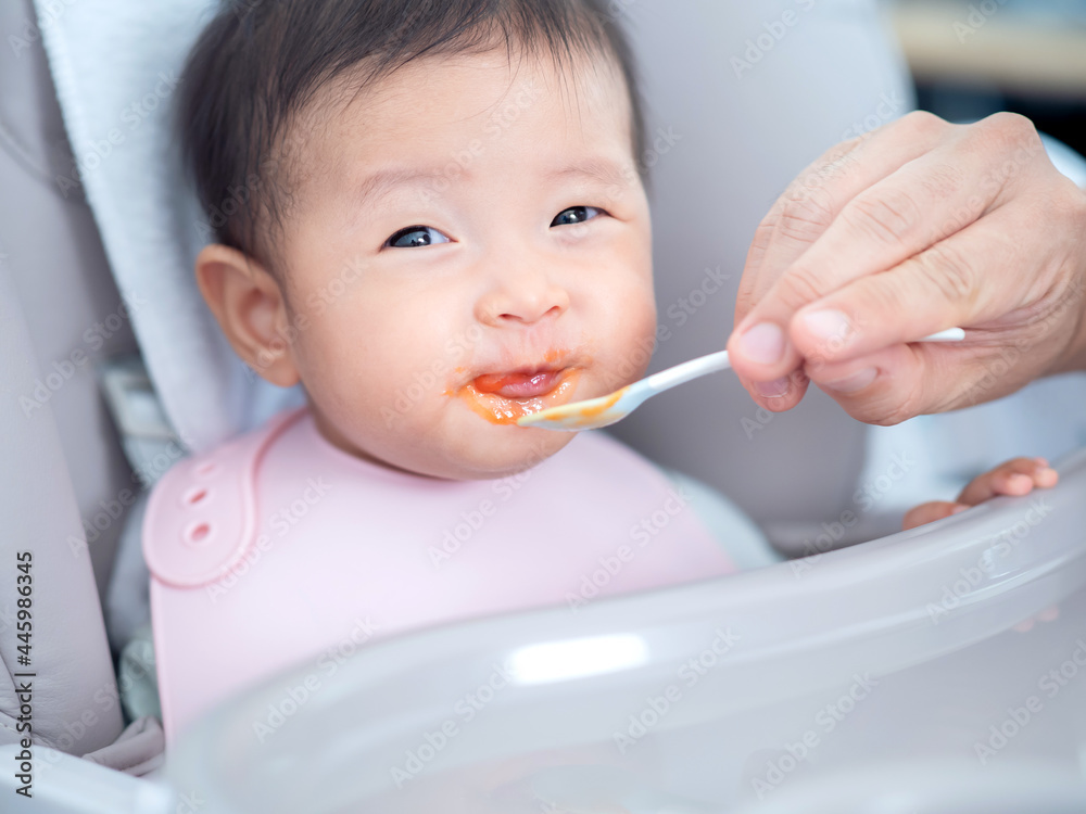 亚洲可爱的小女婴快乐地吃着父母喂养的混合食物