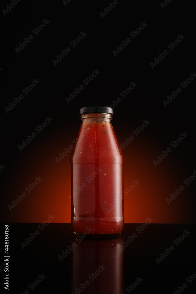 Bottle of chili sauce on dark background