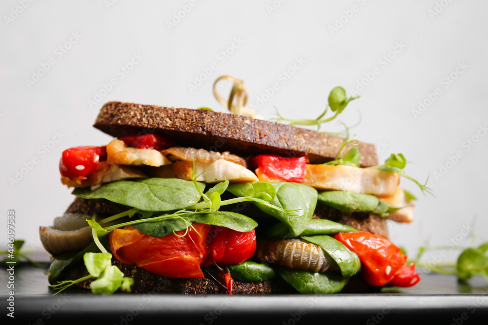 Board with tasty sandwich on light background, closeup