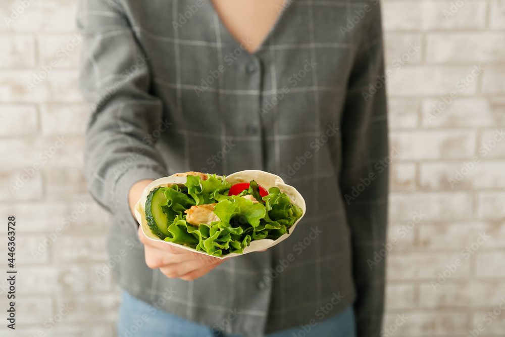 在轻质砖墙附近吃着美味烤肉串的女人，特写