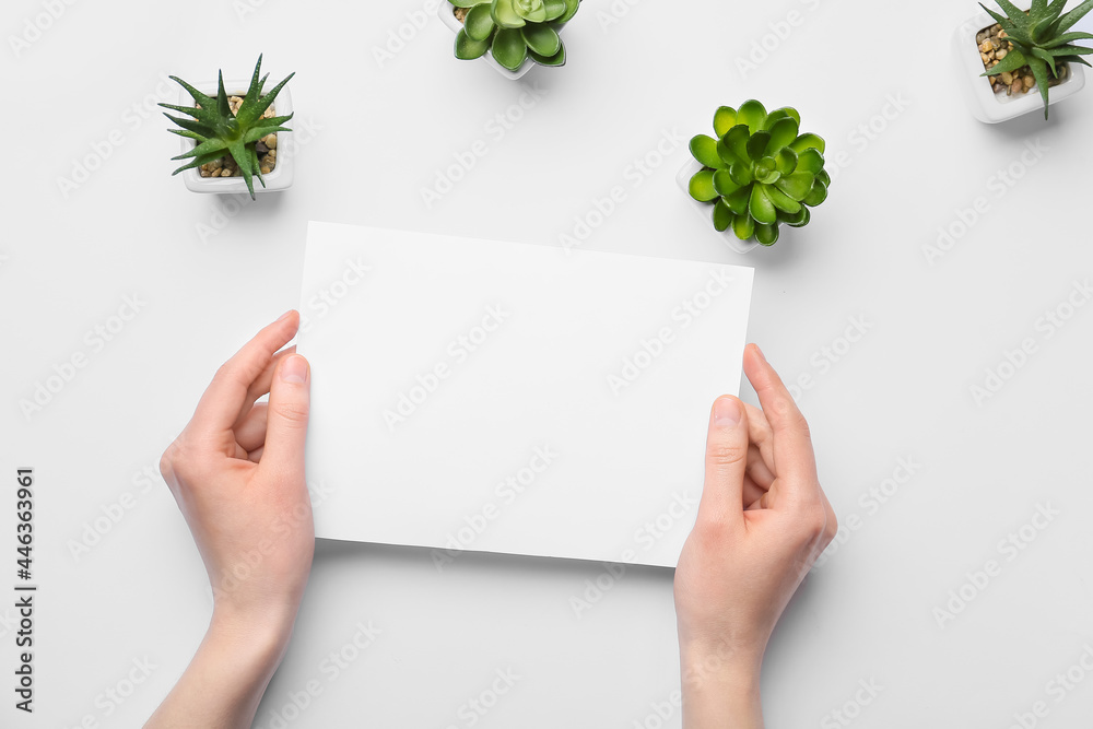 Female hands with blank sheet of paper and succulents on light background