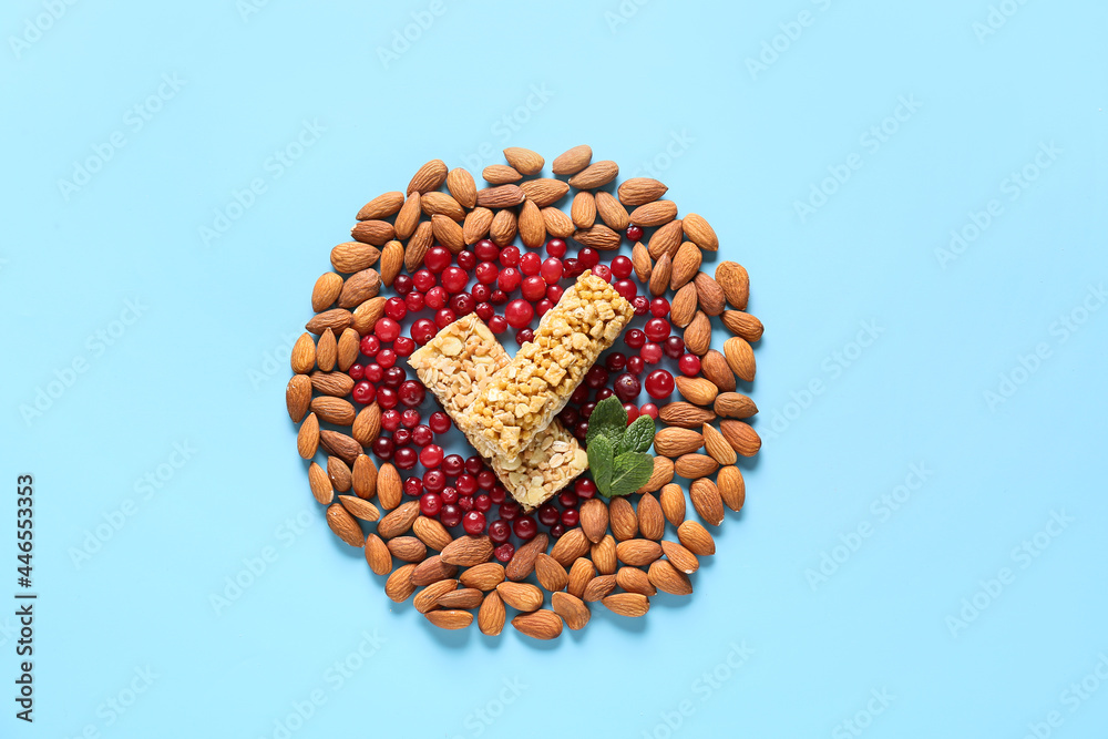 Composition made of healthy cereal bars, cranberries and almonds on color background