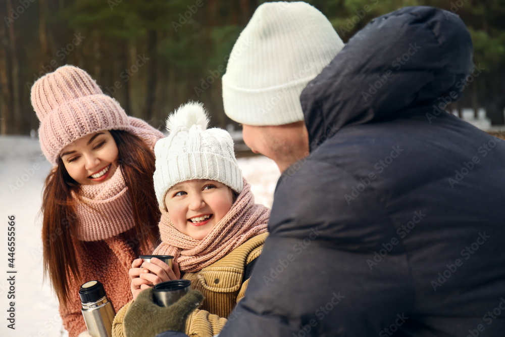 Happy family drinking hot tea in park on winter day