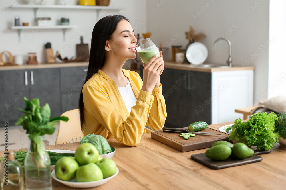 年轻女子在厨房喝健康的绿色奶昔