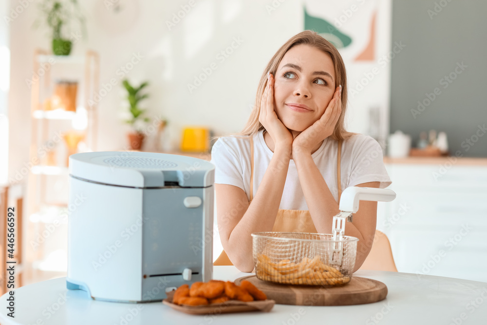 厨房里有油炸锅和小吃的年轻女人