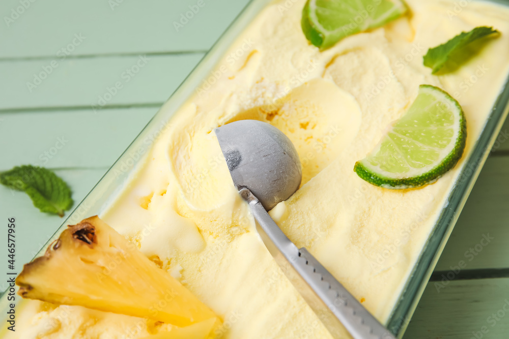 Container with tasty pineapple ice cream on color wooden background