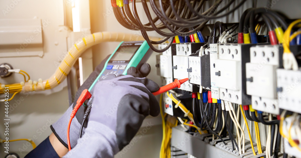 Electrician engineer tests electrical installations and wires on relay protection system. Adjustment