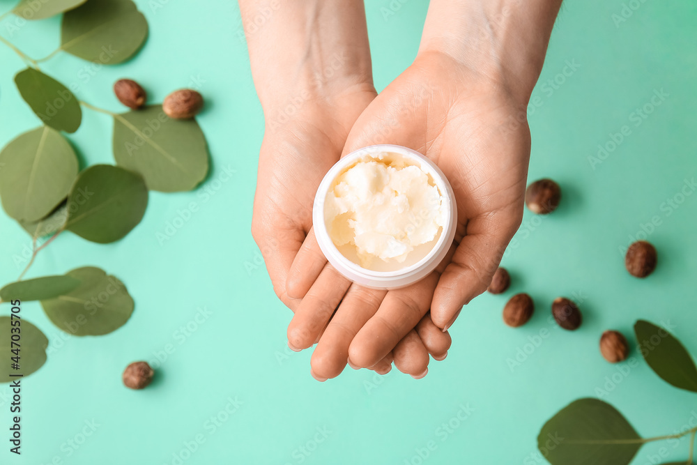 女人拿着彩色背景的乳木果油罐子