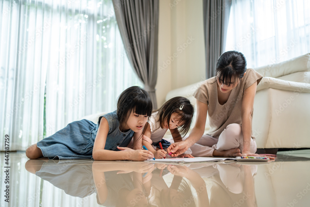 亚洲小兄弟姐妹女孩在地板上与母亲一起画画和彩绘