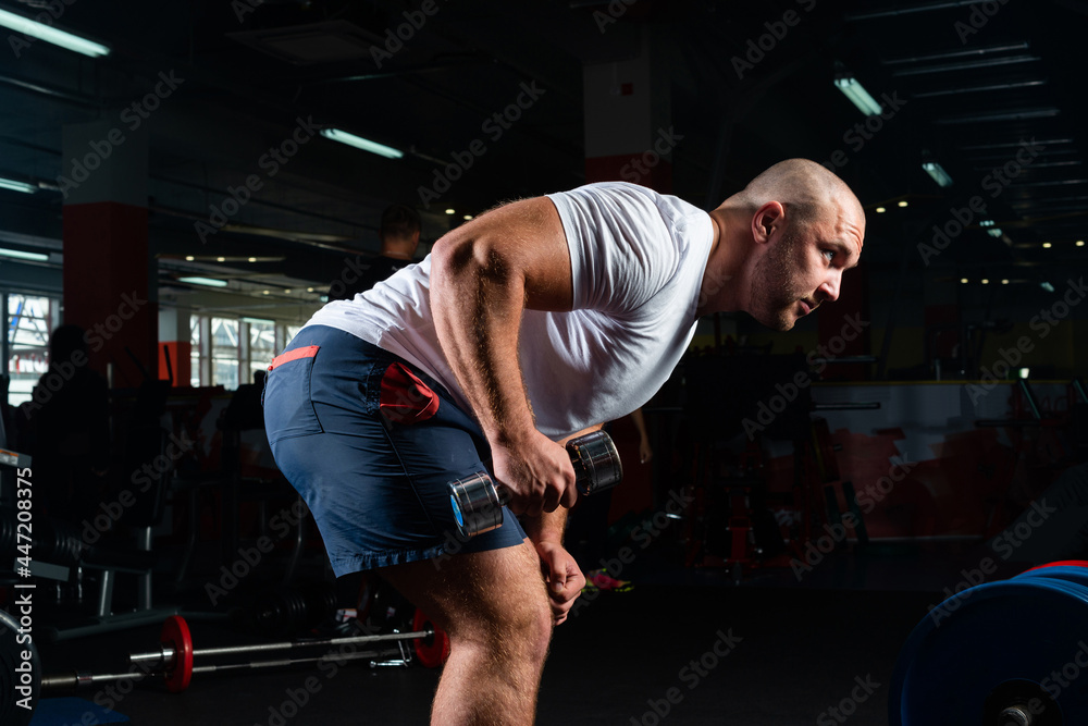 Male bodybuilder engaged with dumbbells in the gym