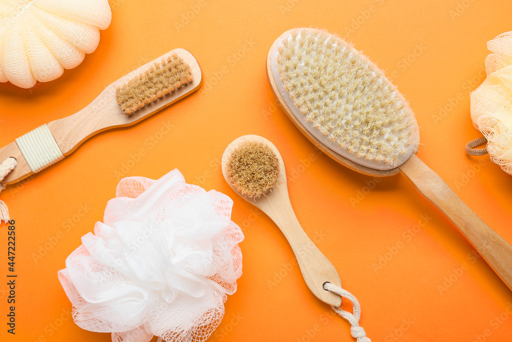 Massage brushes and sponges on color background