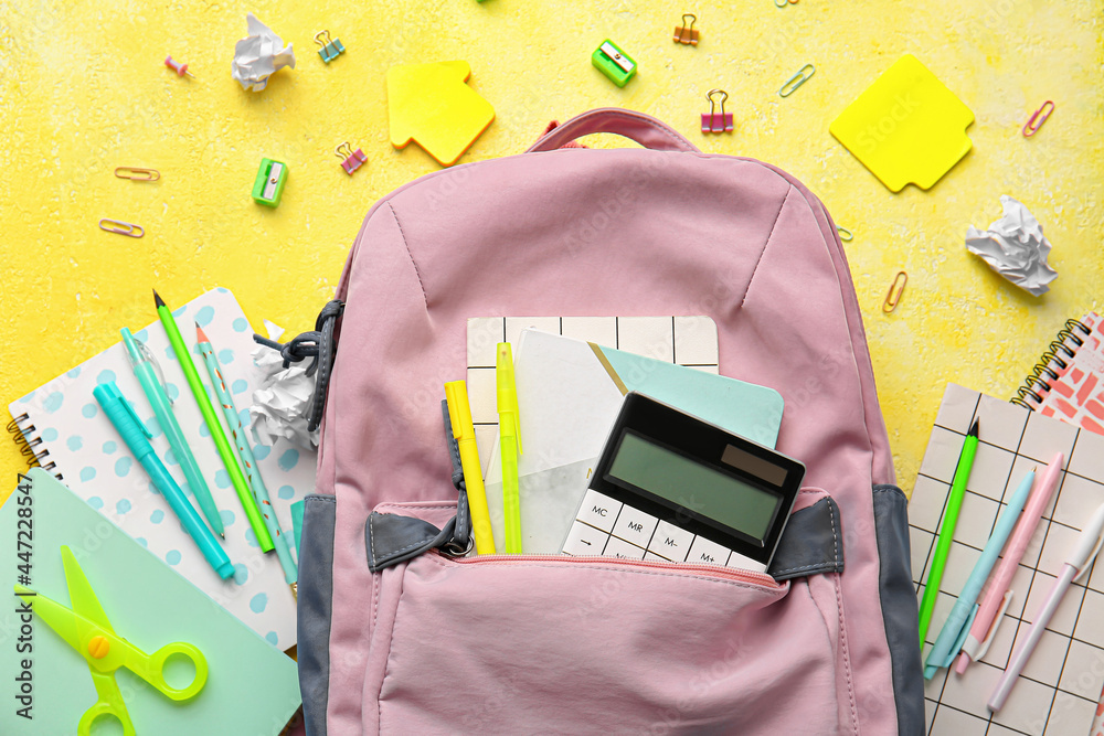 School backpack and stationery on color background