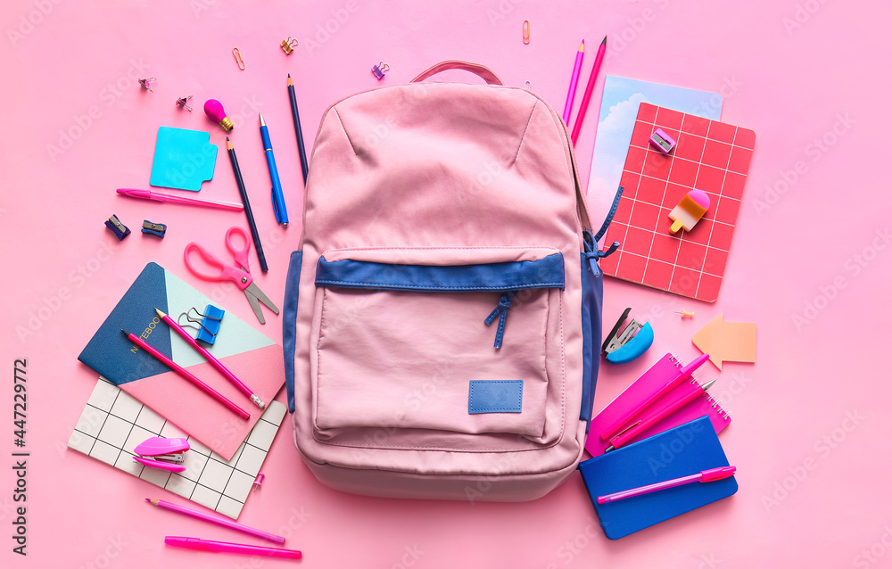 School backpack and stationery on color background