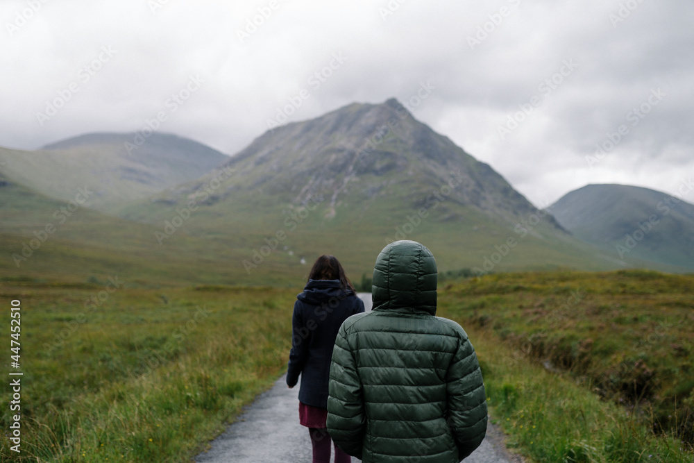 Couple of friends walking through the rain in Glen Etive, Scotland