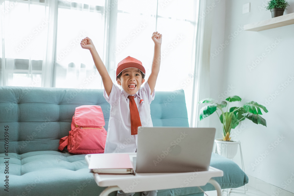 身穿制服的小学生兴奋地在网课上举起手臂