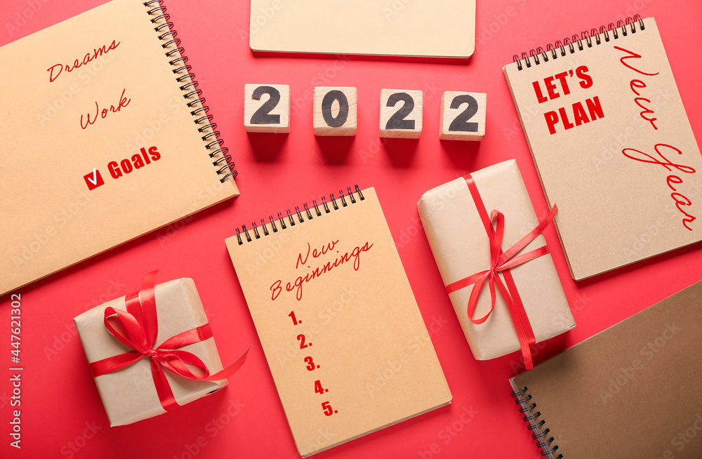 Notebooks with empty to-do list for 2022 year and gifts on color background