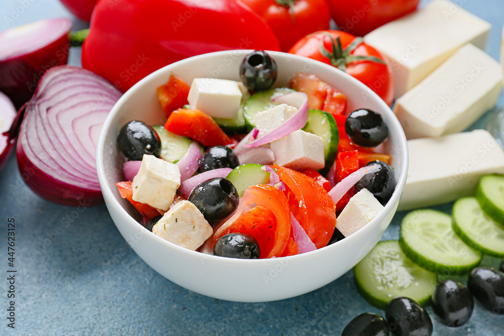 Bowl with tasty Greek salad on color background, closeup