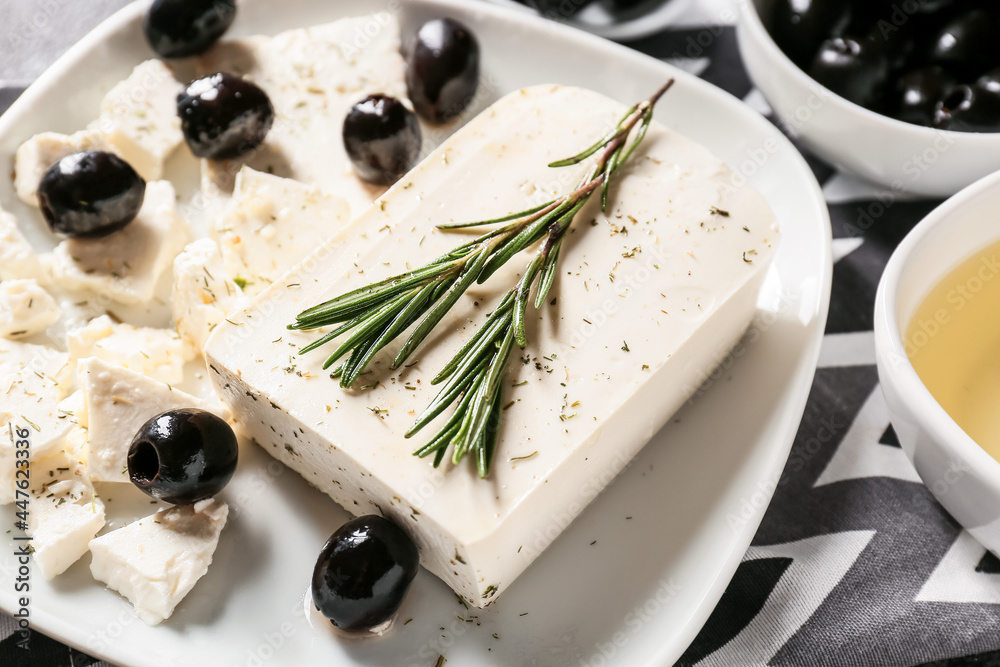 Plate with tasty feta cheese, olives and rosemary on table, closeup