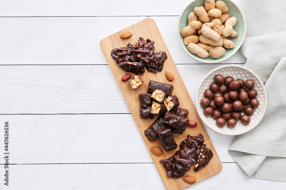 Composition with tasty chocolate candies and nuts on light wooden background