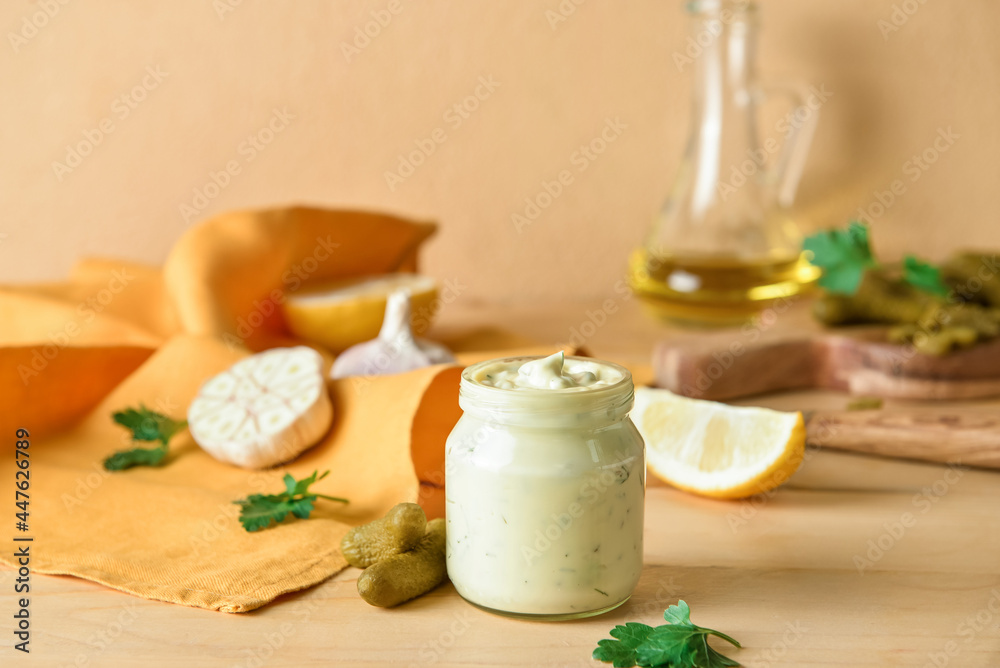 Glass jar with tasty tartare sauce and ingredients on color background